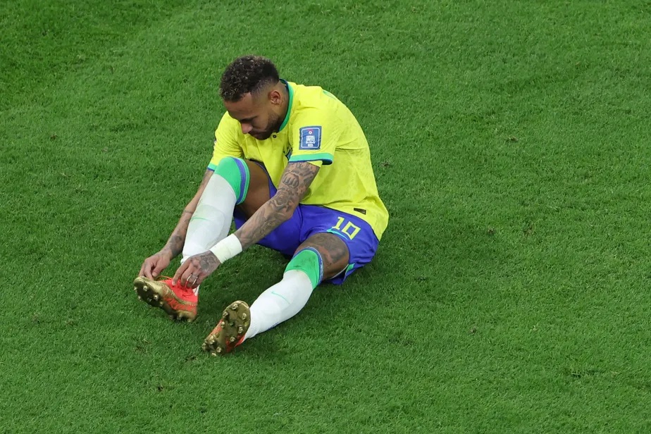 Neymar leva a mão ao tornozelo direito logo antes de pedir substituição, na estreia do Brasil contra Gana Giuseppe Cacace/AFP 